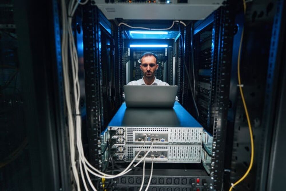 An engineer servicing equipment in the data hall with a laptop