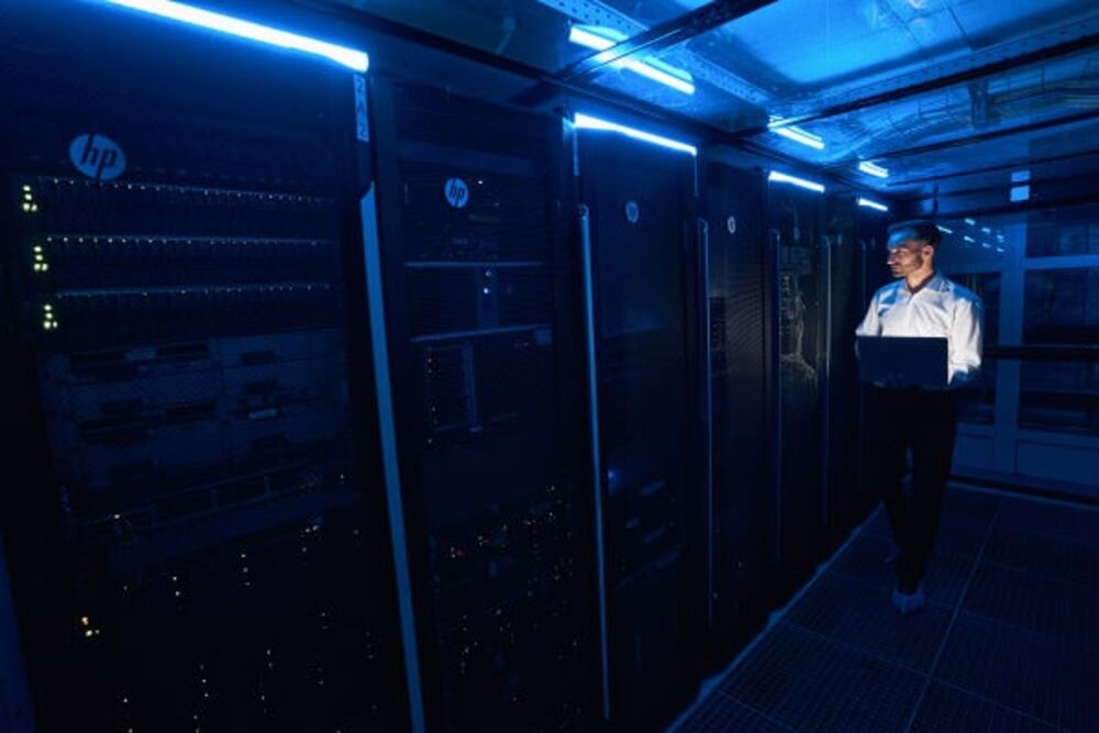 Data hall: rows of server cabinets with an engineer on duty in the cold aisle